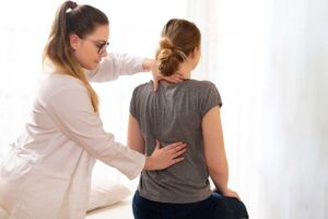 An older adult receiving a gentle chiropractic adjustment from a practitioner in a bright, comfortable clinic.